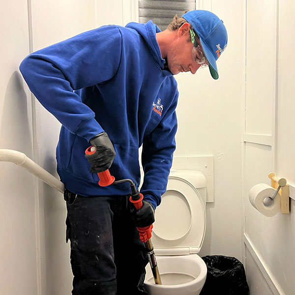 Plumber doing emergency hand auger of blocked toilet