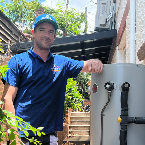 Rhys leaning on gas powered hot water system outside