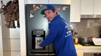 Rhys pouring water from fridge dispenser he just installed smiling