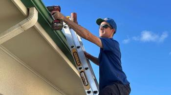 Plumber on ladder working on roof