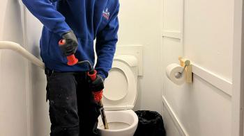 Plumber using a plunger to unblock a toilet