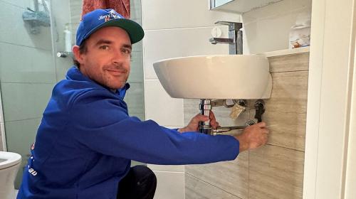 Plumber fixing a leaking tap in bathroom sink